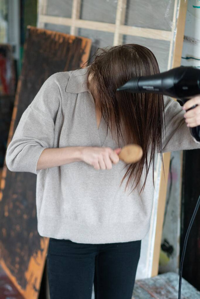 young beautiful woman combing her hair with a hairdryer - Φωτογραφία, εικόνα