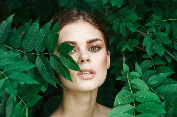 smiling woman skin care bare shoulders green leaves nature close-up - 写真・画像