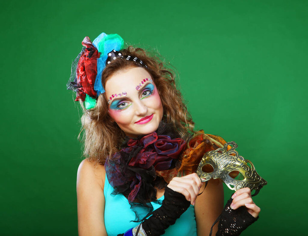 Beautiful young woman with bright makeup and hat holding venetian mask - Foto, immagini