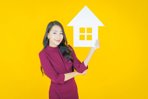 Portrait beautiful young asian woman with house or home paper sign on color background - Photo, image