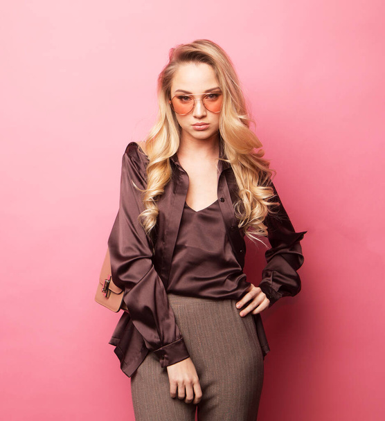 Lifestyle, fashion and people concept: Beautiful young blond woman pose for a photo in trendy clothes over pink background. - Foto, imagen