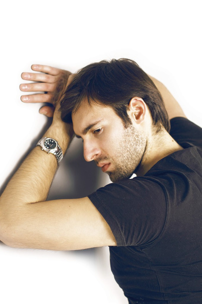 Retrato de moda de un chico guapo enojado con cabello castaño y ojos brillantes en una camiseta negra y un reloj de plata en su mano izquierda malvado mirando fijamente al marco
 - Foto, Imagen