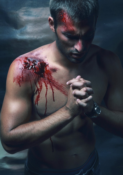 Portrait of handsome masculine bleeding man in jeans who prayin - Zdjęcie, obraz
