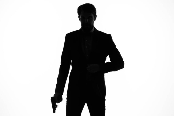 Ο άνθρωπος με το όπλο κοστούμι στα χέρια των συναισθημάτων σιλουέτα φως φόντο - Φωτογραφία, εικόνα