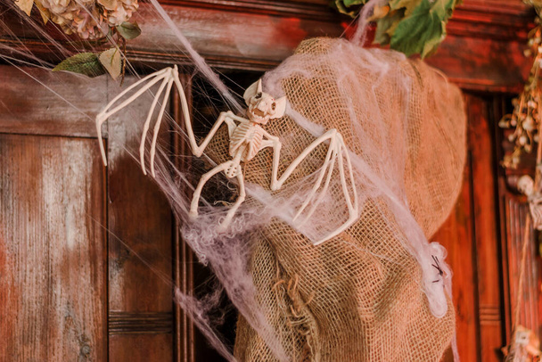 A bat skeleton and a spider web on an old wooden cabinet.Festive holiday decorations.Halloween concept.Copy space for text,selective focus. - Zdjęcie, obraz
