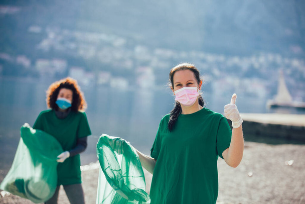 Young female volunteers collecting plastic garbage at beach - Foto, Imagen
