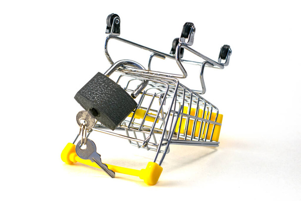 the concept of abandoning the purchase of reasonable consumption is an inverted shopping cart with a padlock on a white background. High quality photo - Photo, Image