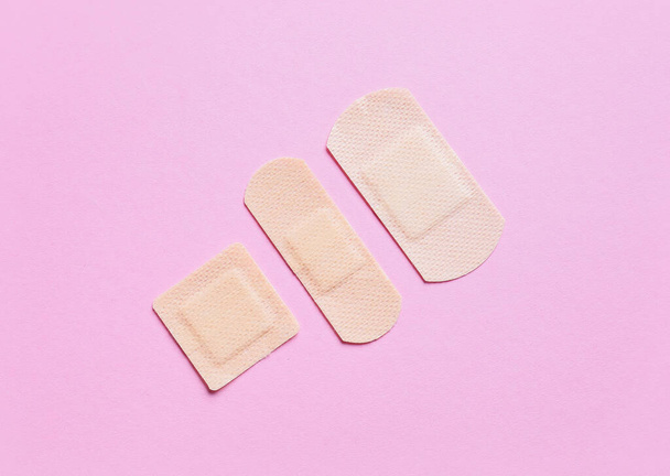 Different medical plasters on pink background - Фото, изображение