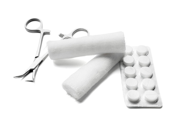 Strumento chirurgico, rotoli di garza medica e pillole su sfondo bianco - Foto, immagini