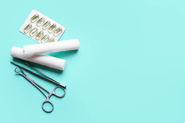Surgical tools, gauze rolls and pills on color background - Фото, зображення