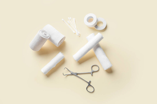 Bandage rolls, medical plaster, cotton buds and surgical tool on color background - Photo, Image
