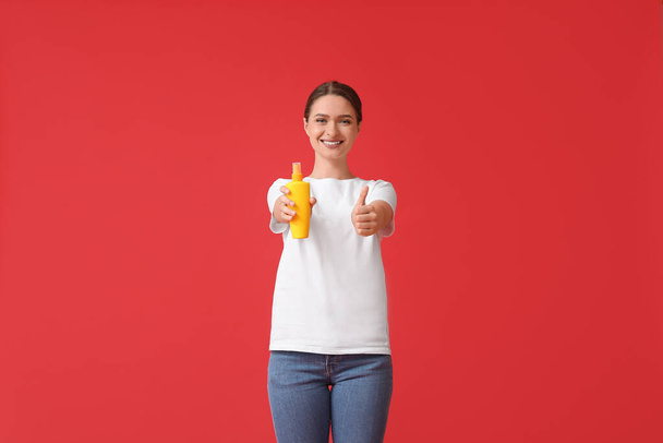 Young woman with mosquito repellent showing thumb-up on color background - Фото, зображення