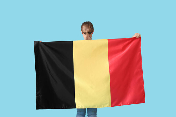 Jonge vrouw met vlag van België op kleur achtergrond, achteraanzicht - Foto, afbeelding