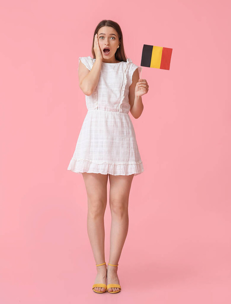 Zaskoczona młoda kobieta z flagą Belgii na tle koloru - Zdjęcie, obraz