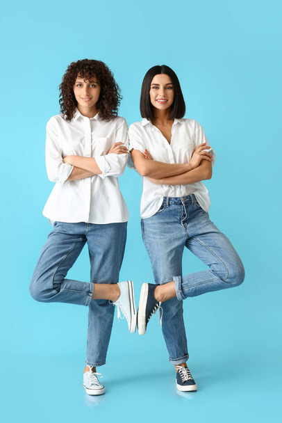 Jonge zussen met gekruiste handen staan op kleur achtergrond - Foto, afbeelding