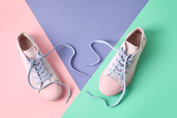 Paar Schuhe mit ungebundenen Schnürsenkeln auf farbigem Hintergrund - Foto, Bild
