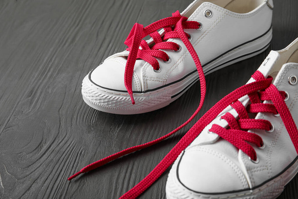 paar schoenen met rode veters op donkere houten achtergrond, close-up - Foto, afbeelding