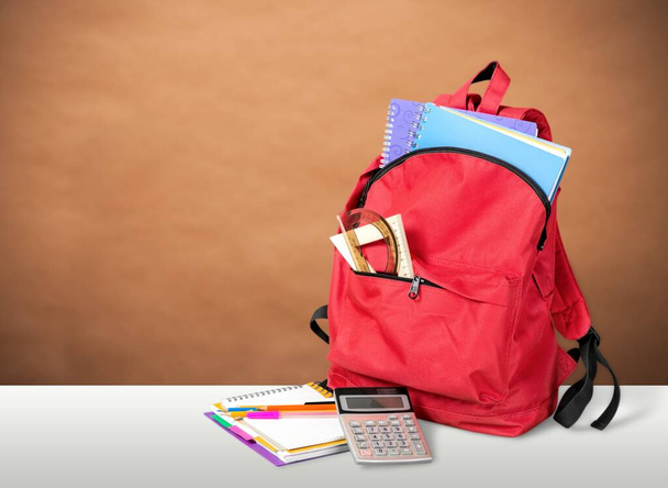 red backpack with school supplies on the table - Fotó, kép