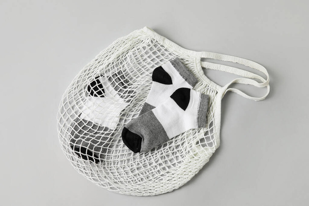 Shopping string bag with socks on grey background - Photo, Image