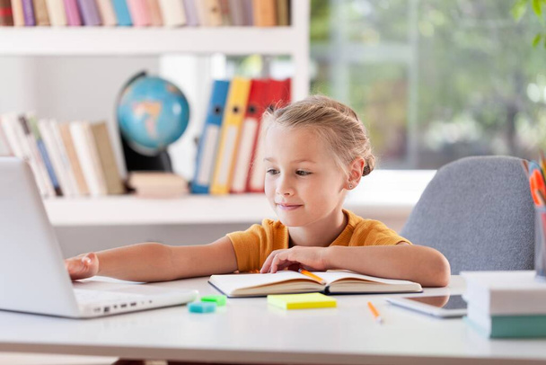 Concepto de educación en el hogar. Chica feliz estudiando en casa con portátil, - Foto, Imagen