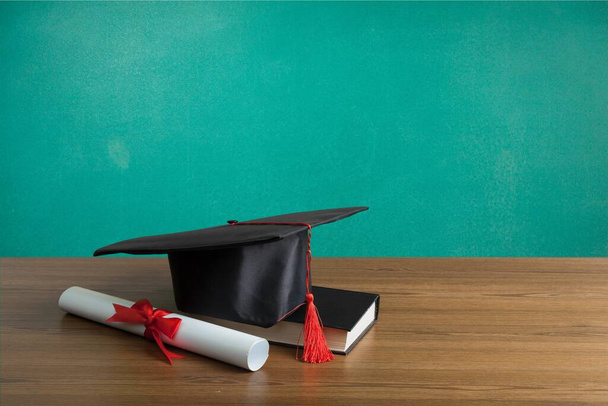graduation hat and diploma and book on green background - Foto, immagini