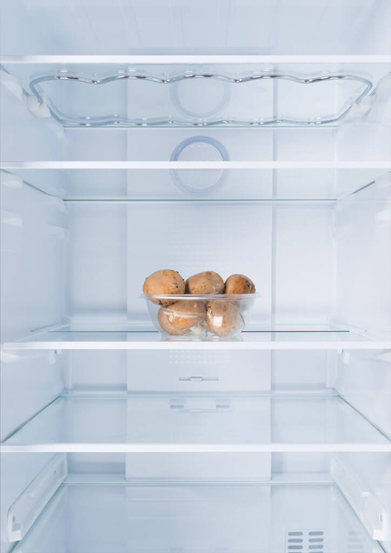 mushrooms in a container, in the refrigerator on a glass shelf, on a white background - Foto, Bild
