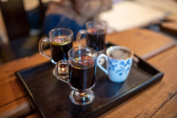 A selective focus shot of glasses of mulled wine on a tray on a wooden table - Foto, afbeelding