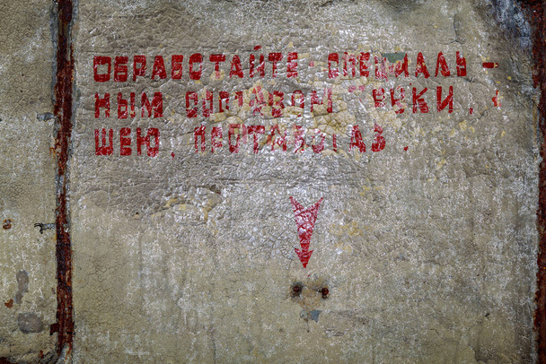 Napis w bunkrze na ścianie w języku rosyjskim: TREAT ze SPECJALNYMI ŚRODKAMI HANDÓW, NECK, ANTI-GAS. Poapokaliptyczne tło - Zdjęcie, obraz