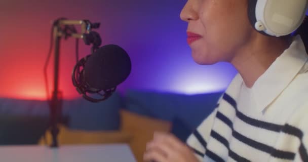 Happy asia lady blogger music influencer grabar un podcast en el ordenador con auriculares y micrófono hablar con el público en el estudio de la sala de estar en casa por la noche. Quedarse en casa, Concepto creador de contenidos. - Metraje, vídeo