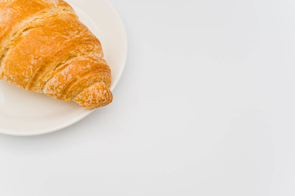 shot of fresh and buttery croissant in a plate on a white background with text space - Фото, изображение