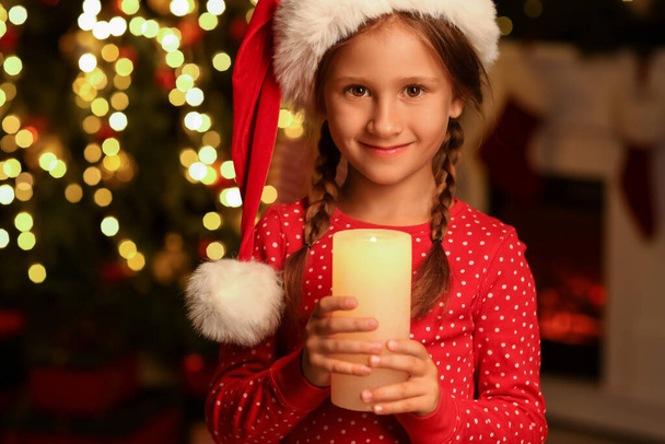 Menina no chapéu de Santa com vela em casa na véspera de Natal - Foto, Imagem