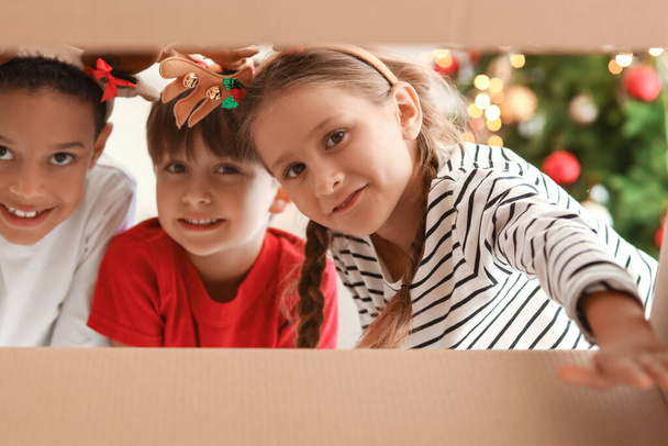 Lindos niños pequeños con caja abierta en Nochebuena, vista desde el interior - Foto, imagen