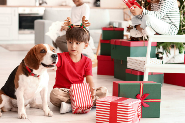 Söpö pieni poika lahjoja ja koira kotona jouluaattona - Valokuva, kuva