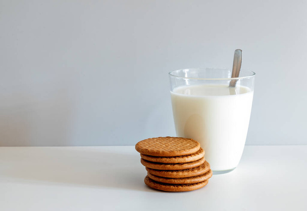 Glass of milk and six round butter biscuits on a white background. - 写真・画像