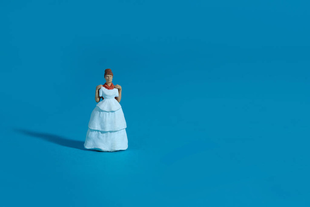 Nők miniatűr emberek próbálnak választani esküvői ruha kék háttérrel. Képfotó - Fotó, kép