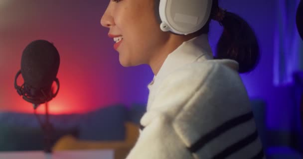 Happy asia lady blogger music influencer grabar un podcast en el ordenador con auriculares y micrófono hablar con el público en el estudio de la sala de estar en casa por la noche. Quedarse en casa, Concepto creador de contenidos. - Imágenes, Vídeo