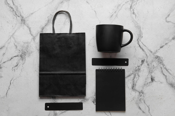 Siyah bardak, kağıt torba ve açık arkaplanda not defteri ile kompozisyon - Fotoğraf, Görsel
