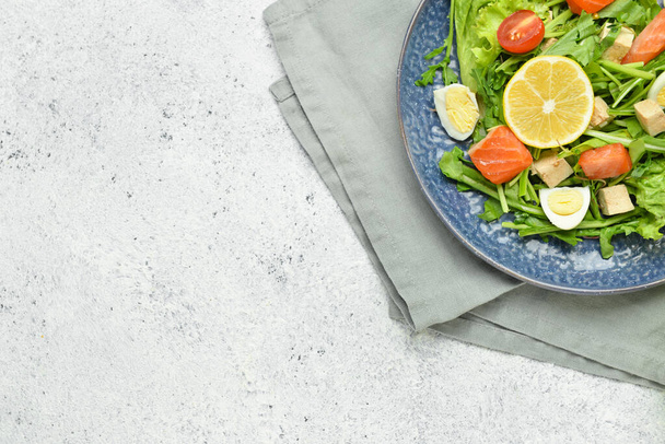 Friss saláta lazaccal és zöldséggel a tányéron, könnyű háttérrel - Fotó, kép