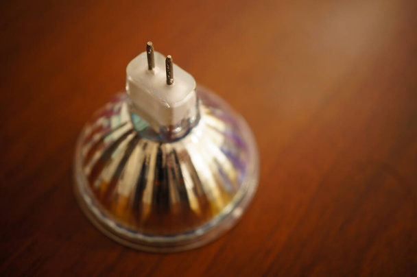 A closeup shot of a halogen light bulb isolated on the wooden table - Photo, image