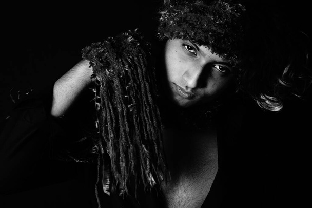 A portrait of a young South Asian male model with a scarf on his head on black background - Фото, изображение
