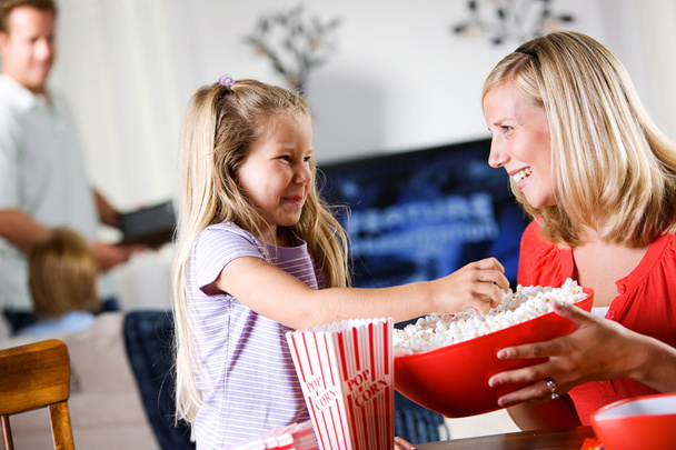 Family: Young Giirl Takes Popcorn From Bowl - Foto, Imagen