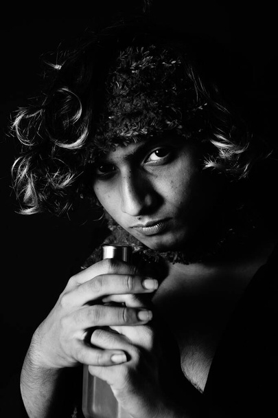 A portrait of a young South Asian male model with a scarf on his head smelling a cologne - Fotó, kép
