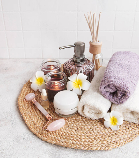 Set de spa, aceite esencial, sal de masaje, velas y flores de frangipani sobre fondo de hormigón gris - Foto, Imagen