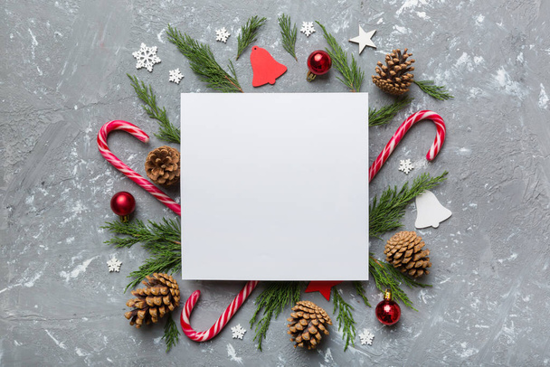 Flat lay Christmas composition. square Paper blank, pine tree branches, christmas decorations on Colored background. Top view, copy space for text. - Photo, Image