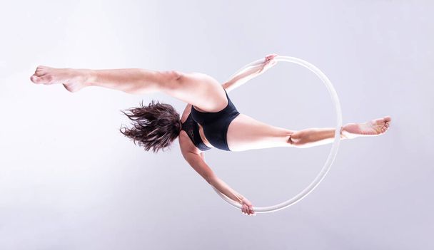 Vista artística de exercícios de ginasta de aro aéreo feminino em um aro aéreo. Isolados  - Foto, Imagem