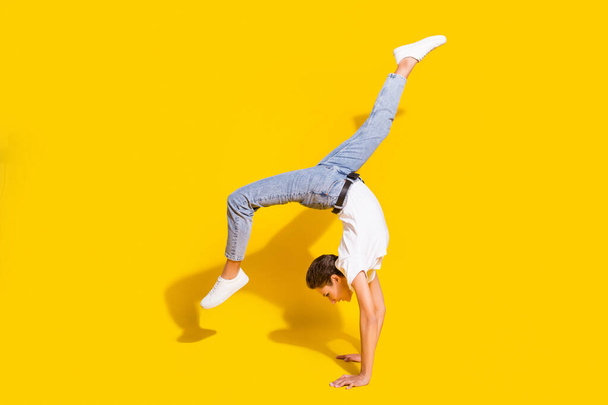 Full body photo of positive happy young woman good mood handstand isolated on yellow color background - Фото, изображение