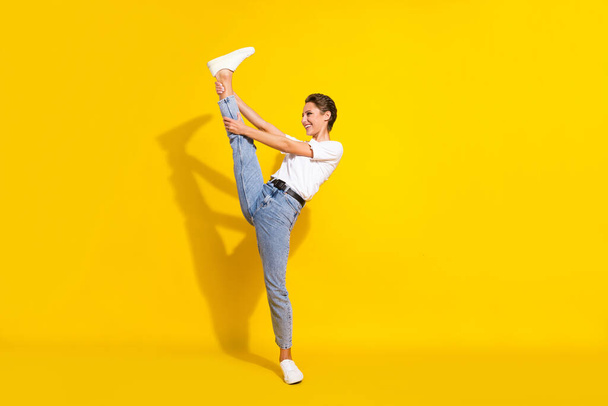 Full length photo of positive happy charming woman flex stretch good mood isolated on yellow color background - 写真・画像