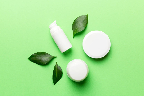 Organic cosmetic products with green leaves on color background. Flat lay. - Valokuva, kuva