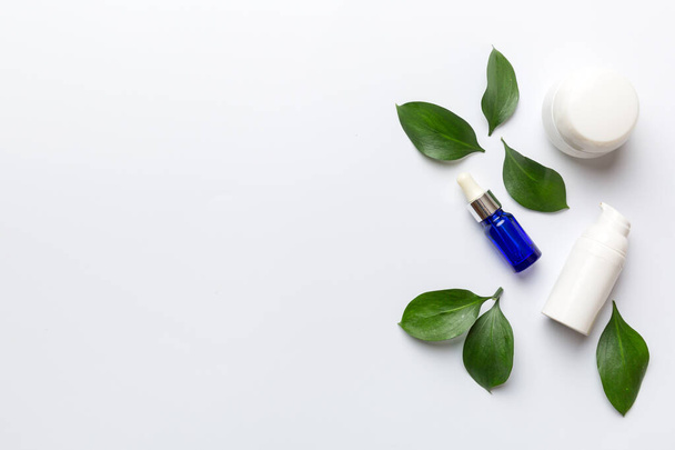 Productos cosméticos ecológicos con hojas verdes sobre fondo blanco. Copiar espacio, plano laico. - Foto, imagen