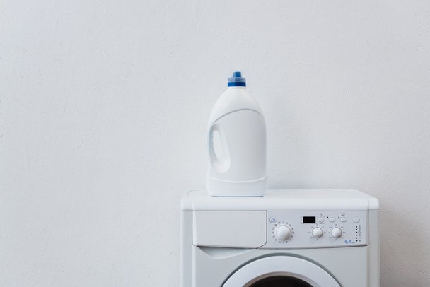 bottiglia di detersivo sulla lavatrice vicino alla parete bianca - Foto, immagini